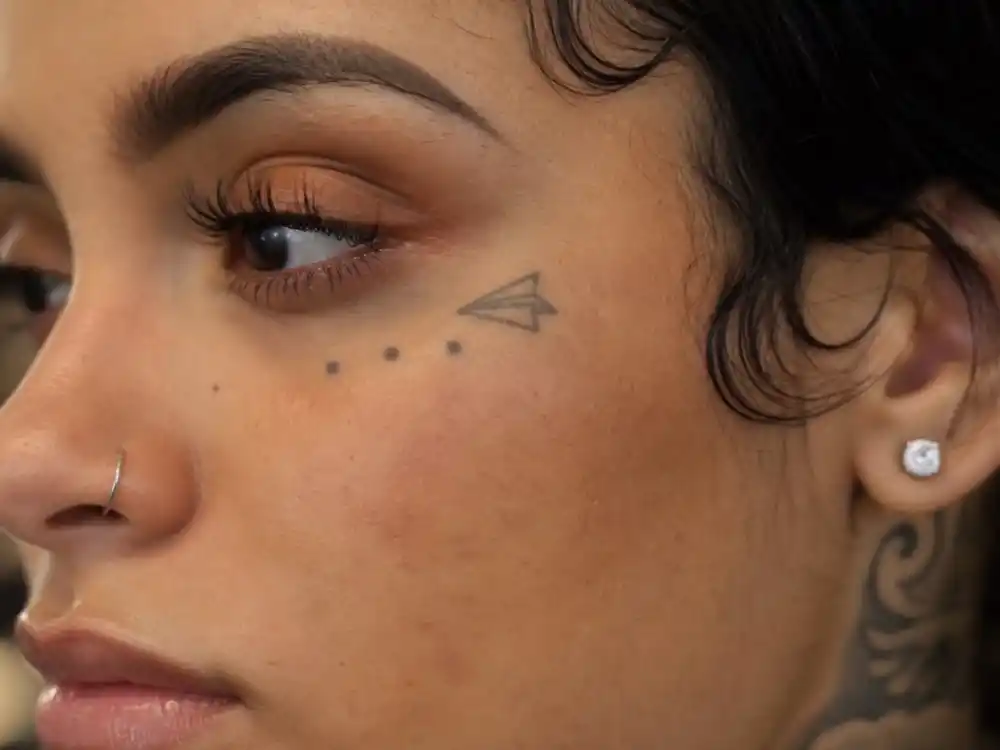 Kehlani tattoos and their meanings — paper airplane wrist tattoo close-up during tattoo studio session