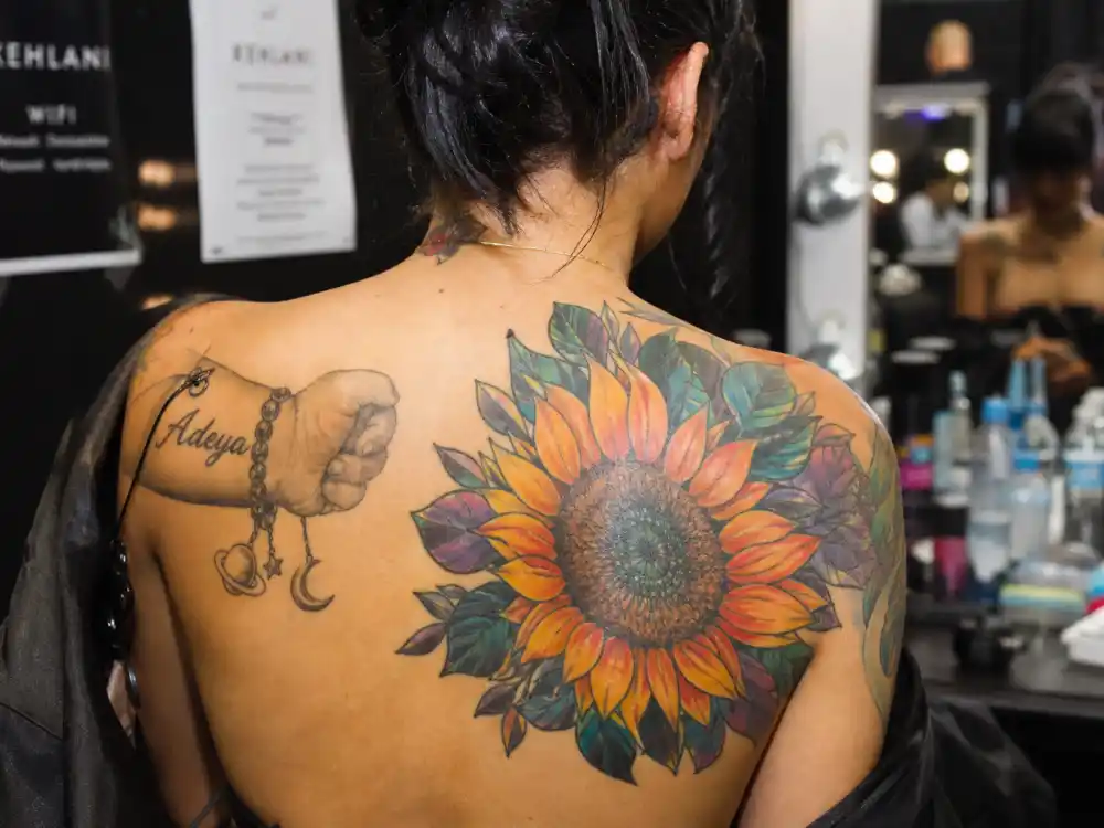 Kehlani tattoos and their meanings — sunflower tattoo on shoulder photographed backstage from behind