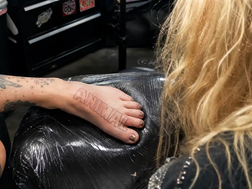 Kesha tattoos and their meanings — ANIMAL outline lettering tattoo on foot honoring her fan community