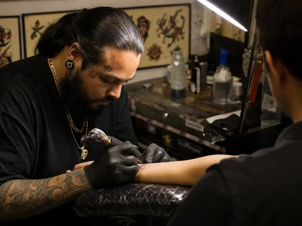 Kid Cudi tattoos and their meanings — celebrity fine-line tattoo artist session with single-needle machine on client forearm in LA studio