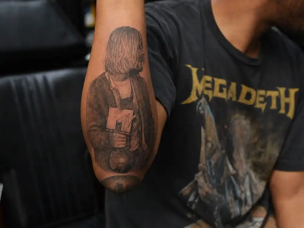 Kid Cudi tattoos and their meanings — Kurt Cobain portrait forearm tattoo in Daniel Johnston shirt at 1992 MTV VMAs recreation