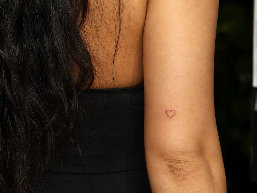 Kylie Jenner tattoos and their meanings — tiny red heart outline tattoo above elbow from 18th birthday first ink