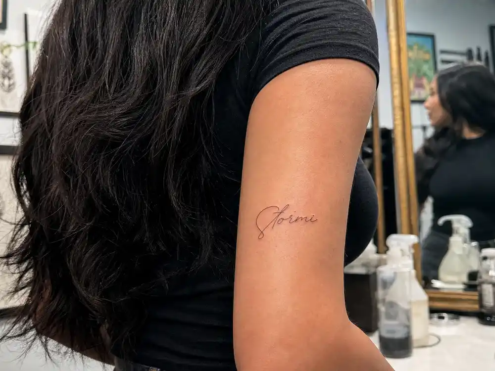 Kylie Jenner tattoos and their meanings — Stormi name tattoo on tricep fine-line black ink from JonBoy birthday party session