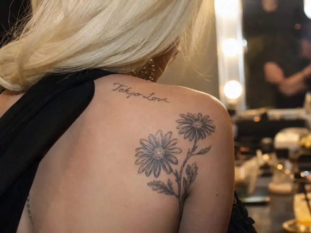 Lady Gaga tattoos and their meanings — daisy cluster and Tokyo Love shoulder script by Nobuyoshi Araki