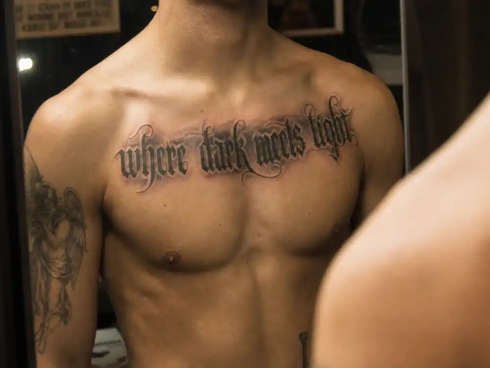 Liam Payne tattoos and their meanings chest script — where dark meets light ombré sternum tattoo mirror close-up on shirtless torso