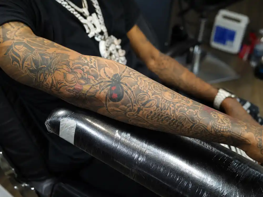 Lil Uzi Vert tattoos and their meanings — close-up of heavily tattooed forearm sleeve with anime motifs and script on rapper arm
