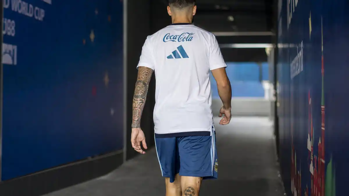 Lionel Messi tattoos and their meanings — athletic soccer player from behind in stadium tunnel showing colorful right arm sleeve and black leg tattoos