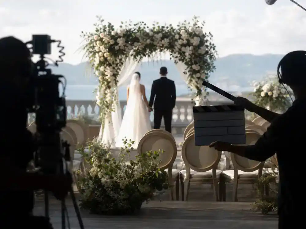 Love Is Blind season 8 cast guide wedding — ceremony film set with floral arch camera crew silhouettes and bride groom silhouettes from behind at altar