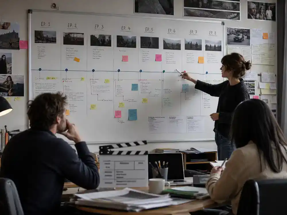 Lupin Netflix cast and episode guide episode structure — production office whiteboard with numbered episode schedule and clapperboard on desk
