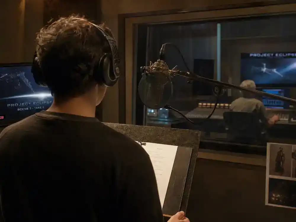 Mandalorian and Grogu movie cast explained Jeremy Allen White — voice actor silhouette from behind in ADR recording booth with studio microphone and engineer