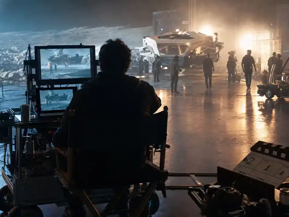 Mandalorian and Grogu movie cast explained Jon Favreau — director silhouette from behind in director chair viewing monitors on sci-fi film set