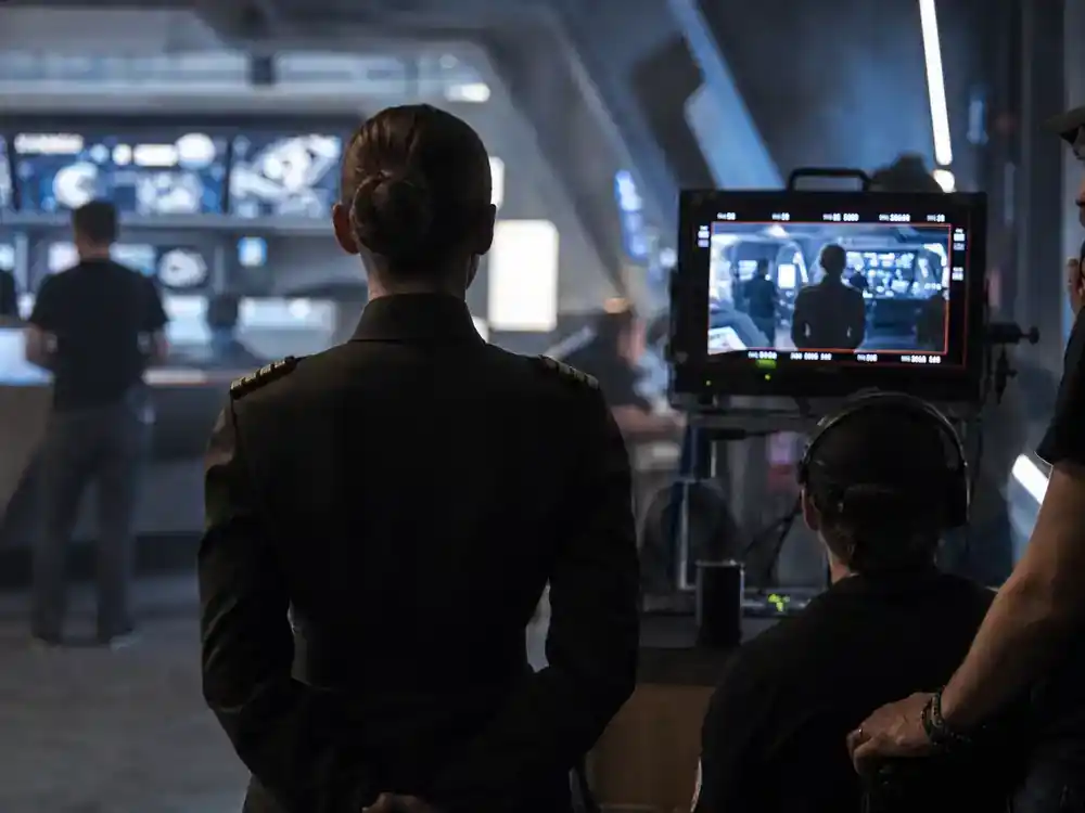 Mandalorian and Grogu movie cast explained Sigourney Weaver — officer uniform silhouette on sci-fi command set from behind facing director monitor