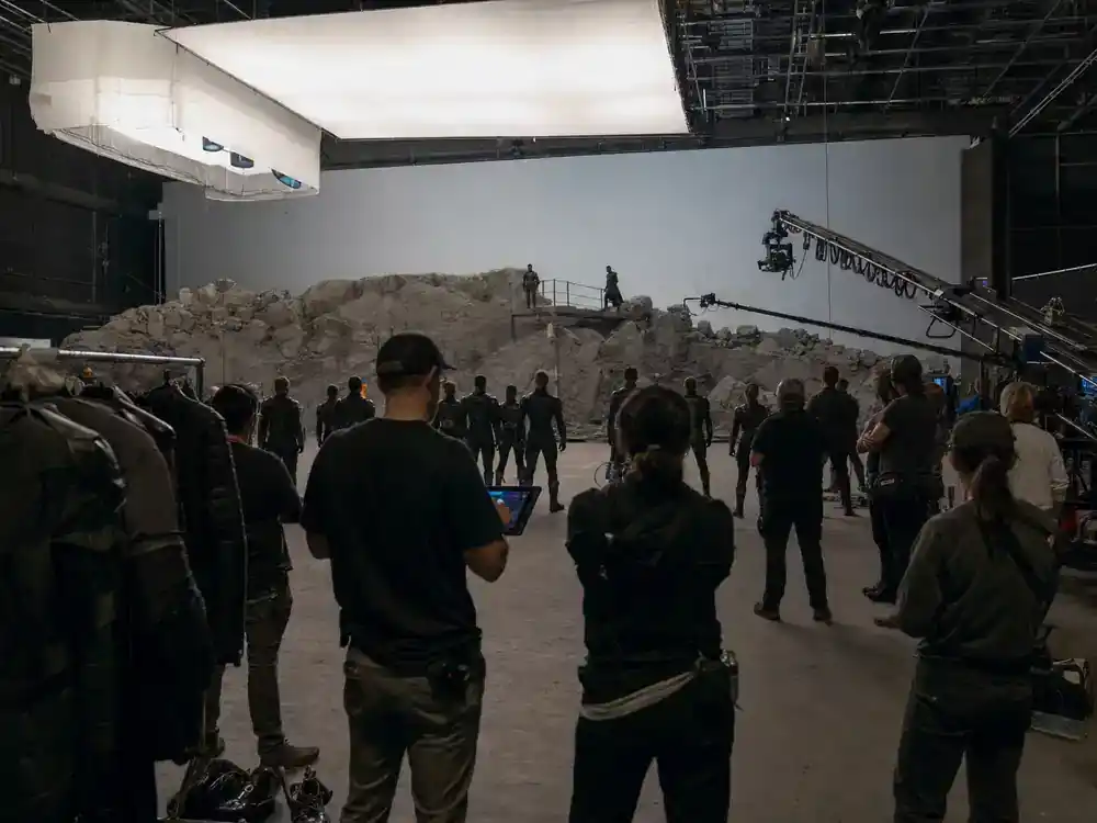Marvel Cinematic Universe phase 6 movies cast guide Avengers Doomsday — ensemble cast silhouettes rehearsing on blockbuster action film soundstage from behind