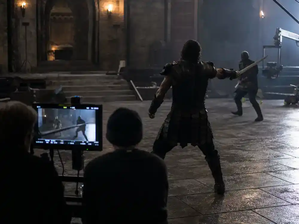 Masters of the Universe movie 2026 cast guide Nicholas Galitzine He-Man — hero costume rehearsal silhouette from behind on fantasy film set with sword props