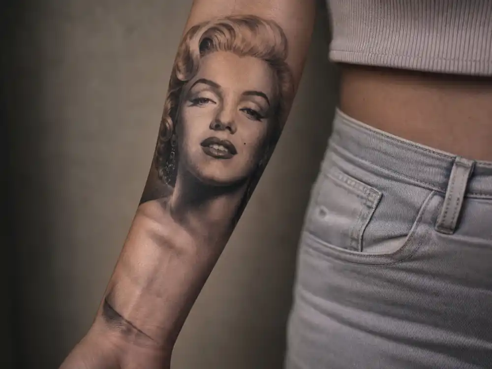 Megan Fox tattoos and their meanings — detailed black-and-grey Marilyn Monroe portrait tattoo on inner right forearm