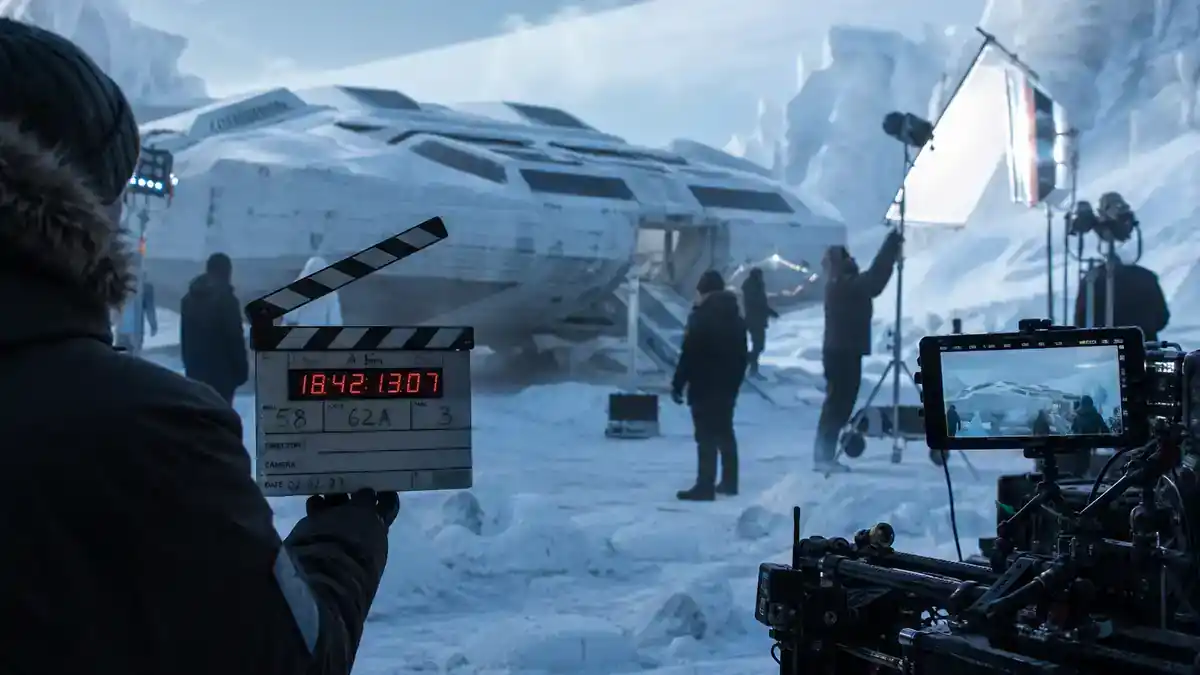 Mickey 17 movie cast and plot explained — icy alien planet film set with spacecraft hull and crew silhouettes in cold weather gear at blue dawn
