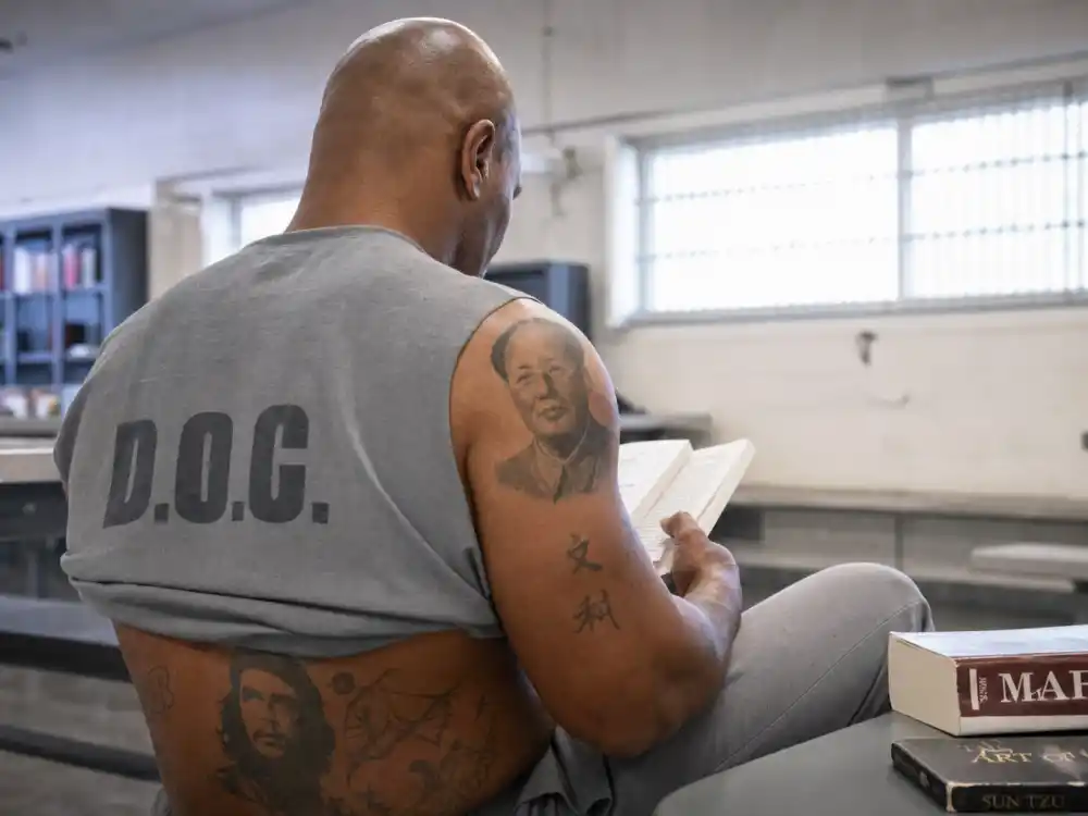 Mike Tyson tattoos and their meanings — prison-era Mao and Che portrait tattoos visible while reading in institutional setting