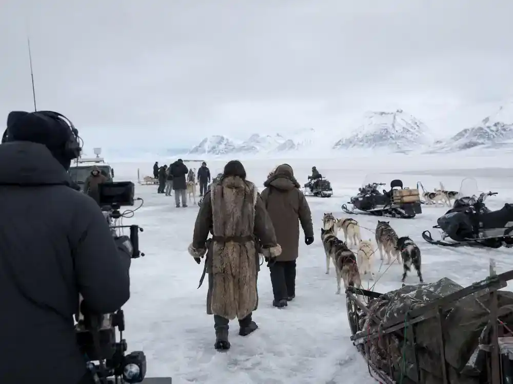 Mission Impossible 8 cast and filming facts Arctic Svalbard — crew with sled dogs on icy tundra location shoot, actors in winter gear from behind