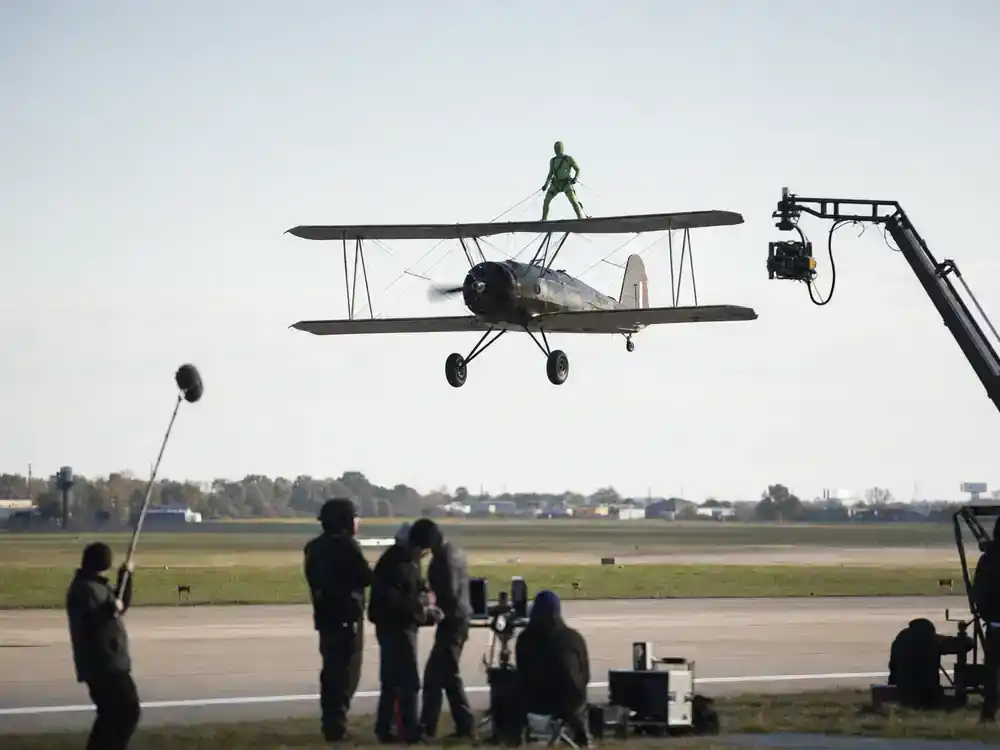 Mission Impossible 8 cast and filming facts biplane stunt — vintage aircraft stunt rehearsal on airfield with greenscreen pilot suit and ground crew filming