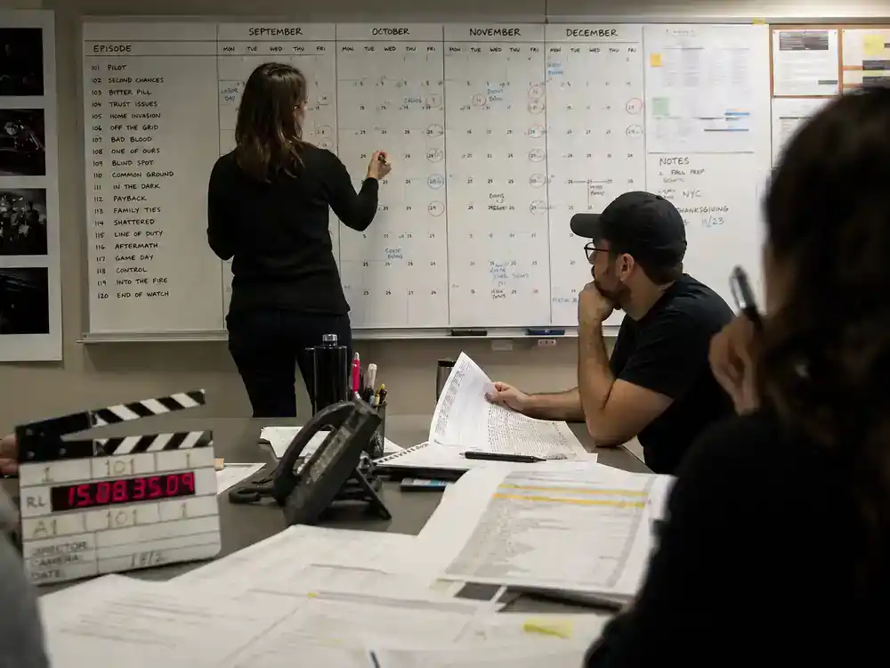 NCIS franchise 2026 cast and spinoff guide Season 23 — network TV fall season planning board with broadcast calendar clapperboard and episode schedule printouts