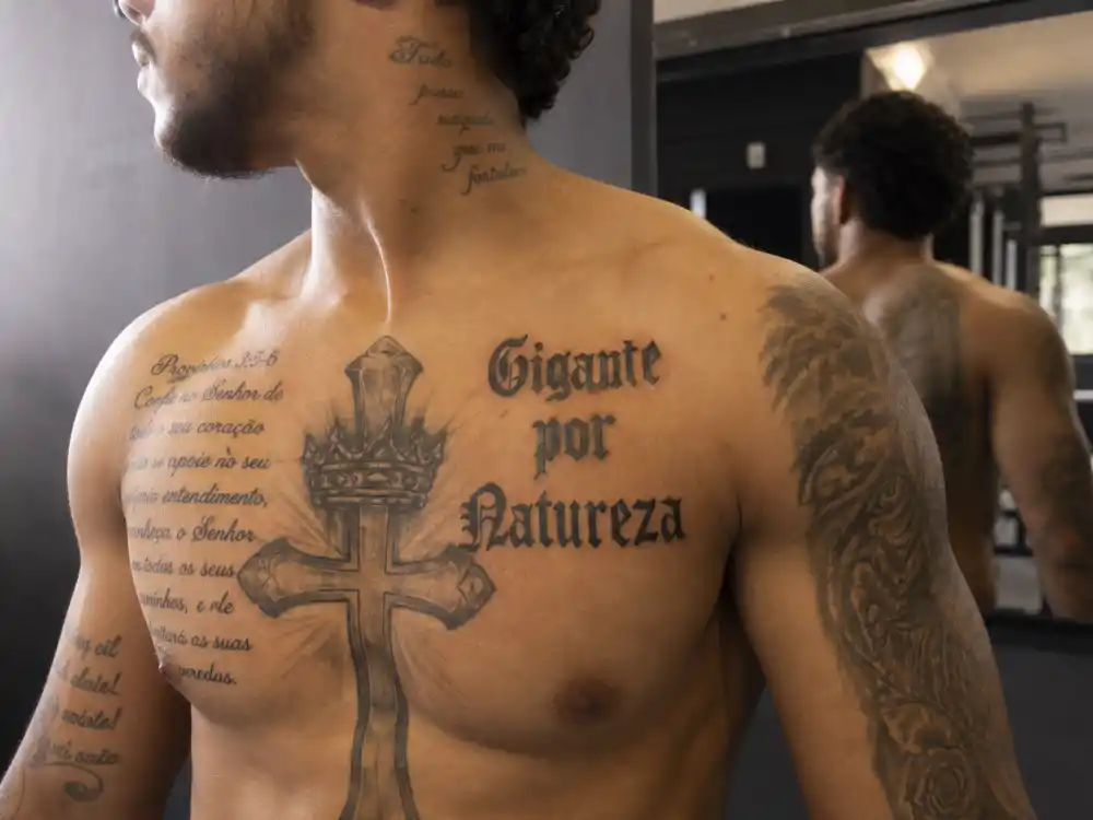 Neymar tattoos and their meanings chest script — cross with crown biblical lettering and Gigante por Natureza phrase on torso