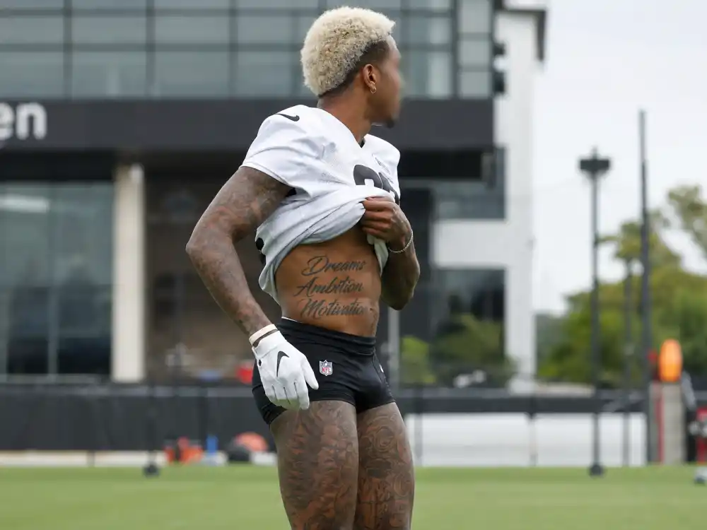 Odell Beckham Jr tattoos and their meanings — adapt to survive torso script tattoo revealed under practice jersey side angle