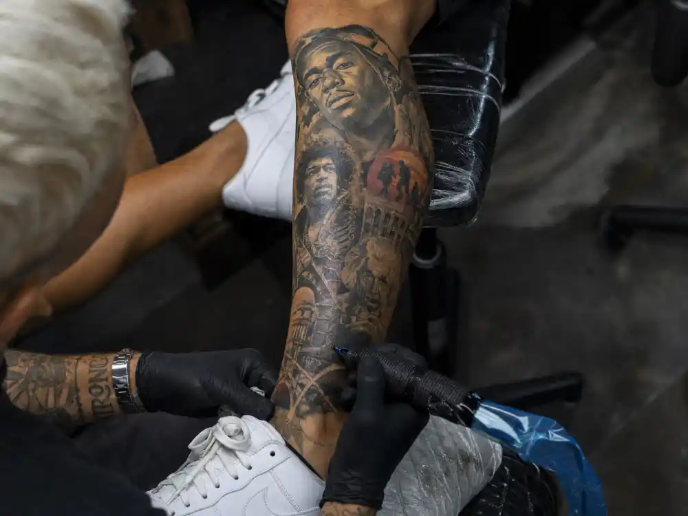 Odell Beckham Jr tattoos and their meanings — colorful legacy leg sleeve with portrait tattoos on calf in studio close-up
