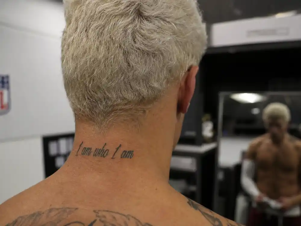 Odell Beckham Jr tattoos and their meanings — I am who I am neck script tattoo in locker room mirror over-shoulder angle