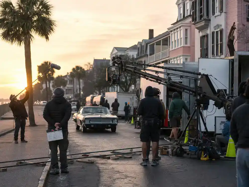 Outer Banks season 5 cast and filming guide Charleston — film crew on historic coastal street at dawn with camera crane and production vans
