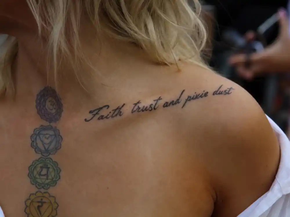 Paris Jackson tattoos and their meanings — Faith trust and pixie dust collarbone script with colorful chakra chest tattoos