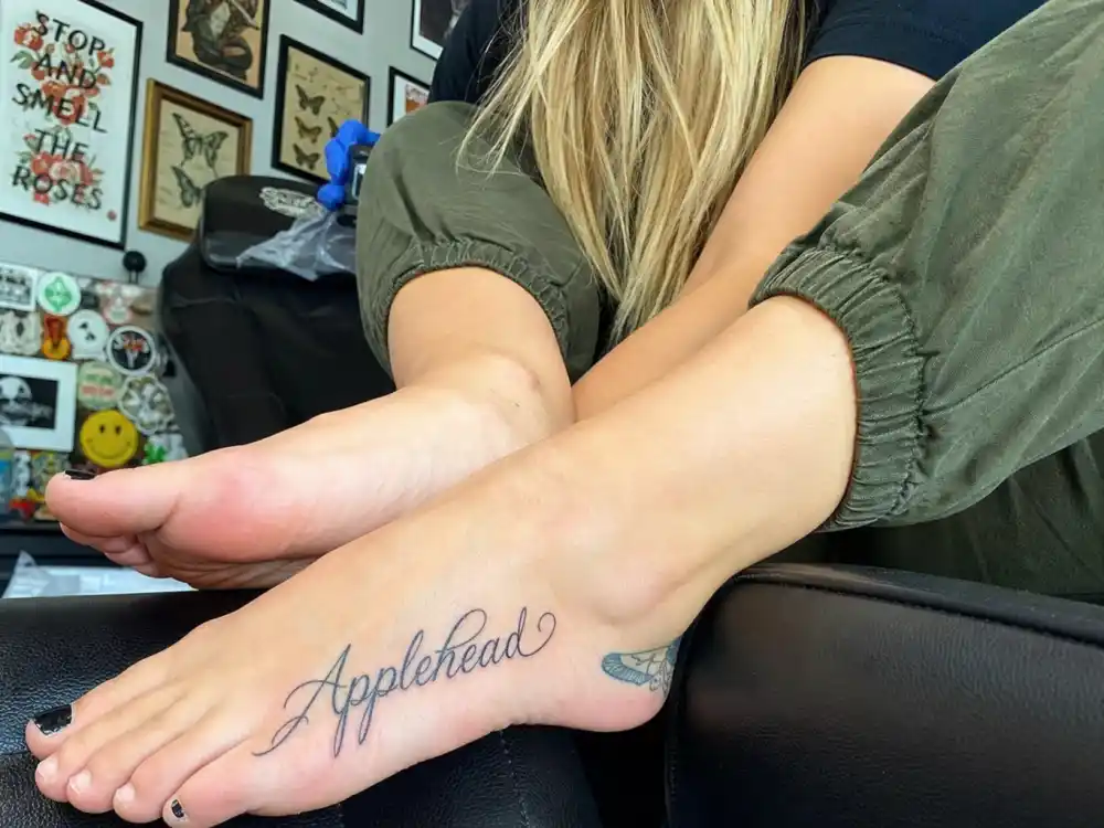 Paris Jackson tattoos and their meanings — Applehead foot script tattoo honoring her father nickname in studio chair close-up