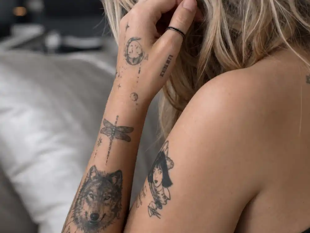 Paris Jackson tattoos and their meanings — close-up of wolf head dragonfly forearm ink and tiny artist portrait tattoos