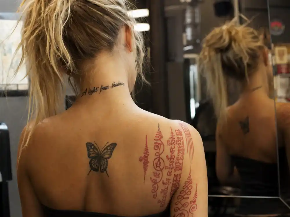 Paris Jackson tattoos and their meanings — A light from the shadows neck script with Sanskrit shoulder and butterfly back tattoos