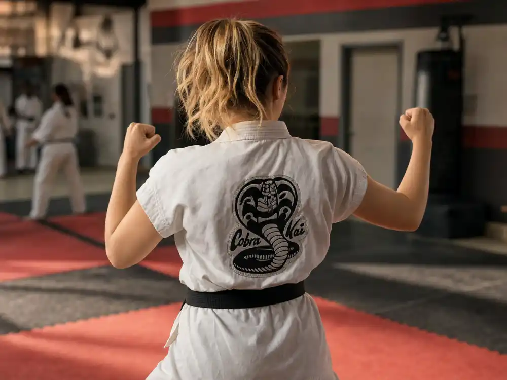Peyton List tattoos and their meanings Cobra Kai — athletic blonde actress from behind in karate gi showing clean uninked forearms and shoulders