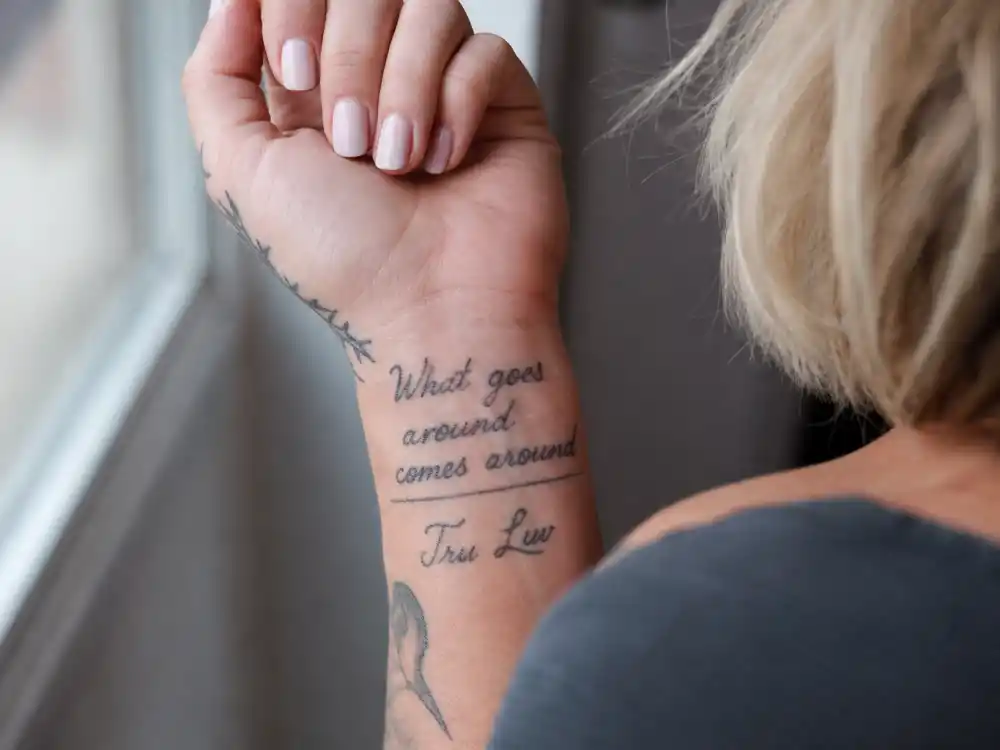Pink tattoos and their meanings — close-up of What goes around comes around wrist script and Tru Luv matching ink