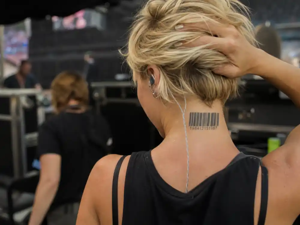 Pink tattoos and their meanings — Missundaztood barcode tattoo on back of neck photographed backstage from behind