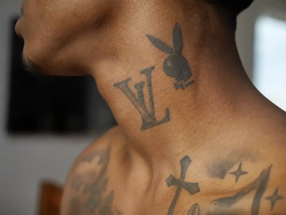 Playboi Carti tattoos and their meanings — close-up of neck V letter and playboy bunny rabbit tattoo side profile documentation