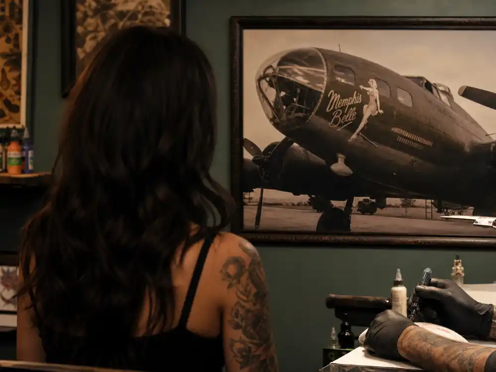 Rose McGowan tattoos and their meanings grandfather plane — WWII bomber nose art design that inspired her shoulder pin-up tattoo