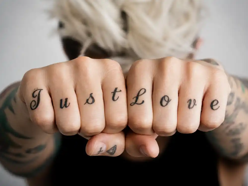 Ruby Rose tattoos and their meanings Just Love — knuckle script LGBT advocacy tattoo with colorful forearm sleeve