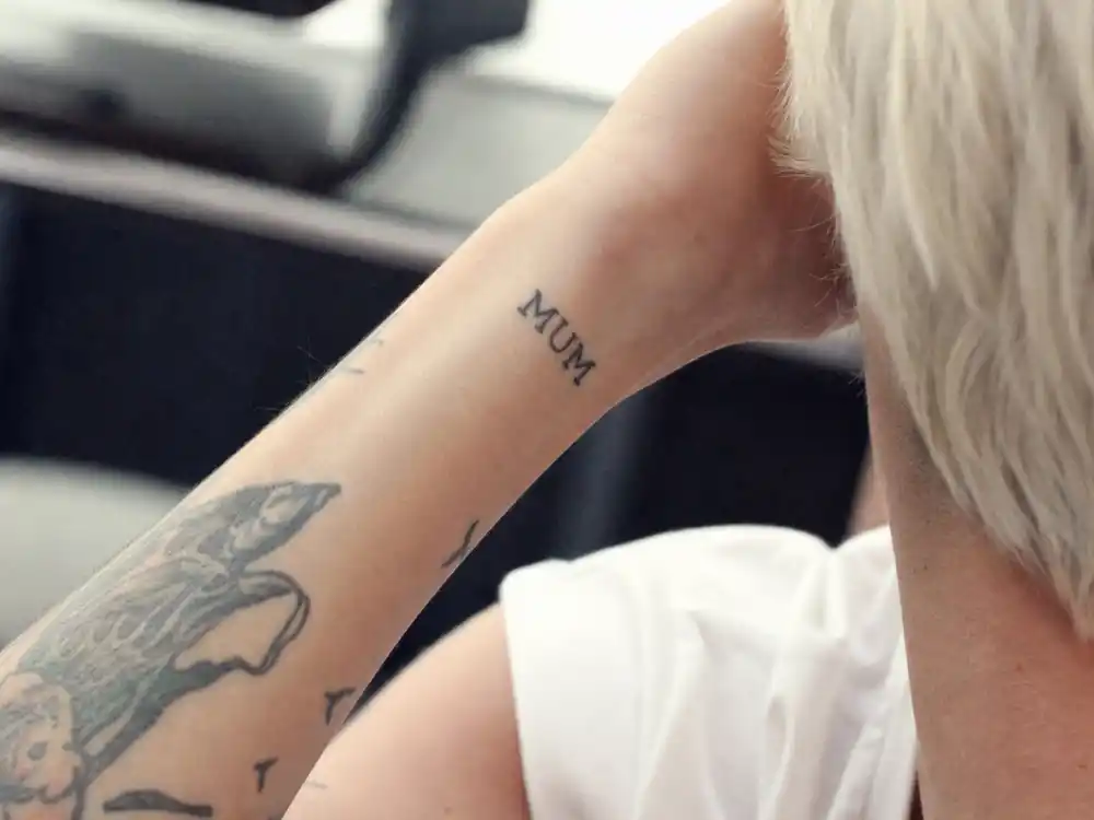 Ruby Rose tattoos and their meanings MUM — wrist script tattoo honoring mother with platinum blonde hair visible