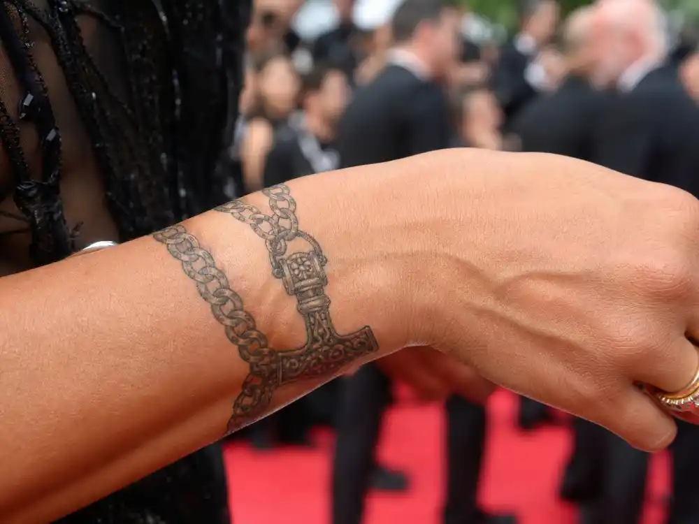 Scarlett Johansson tattoos and their meanings — delicate bracelet wrist tattoo with Thor hammer charm at film festival