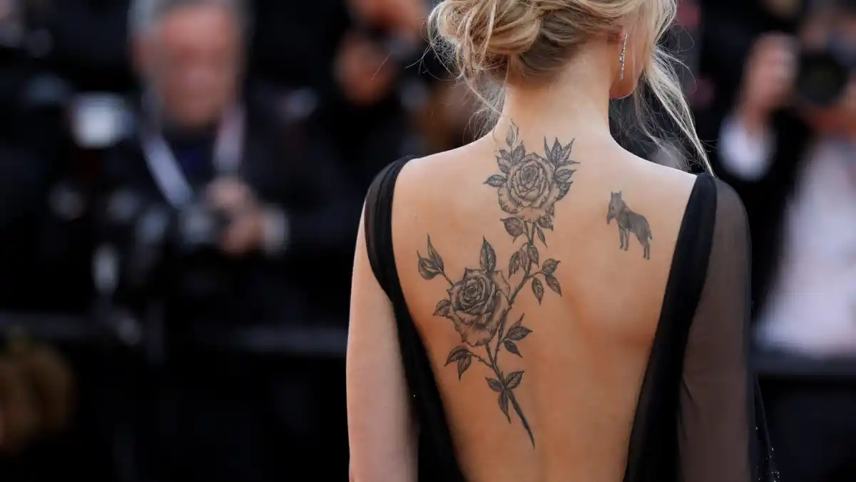 Scarlett Johansson tattoos and their meanings — actress seen from behind at red carpet premiere with rose vine and lamb back tattoos visible