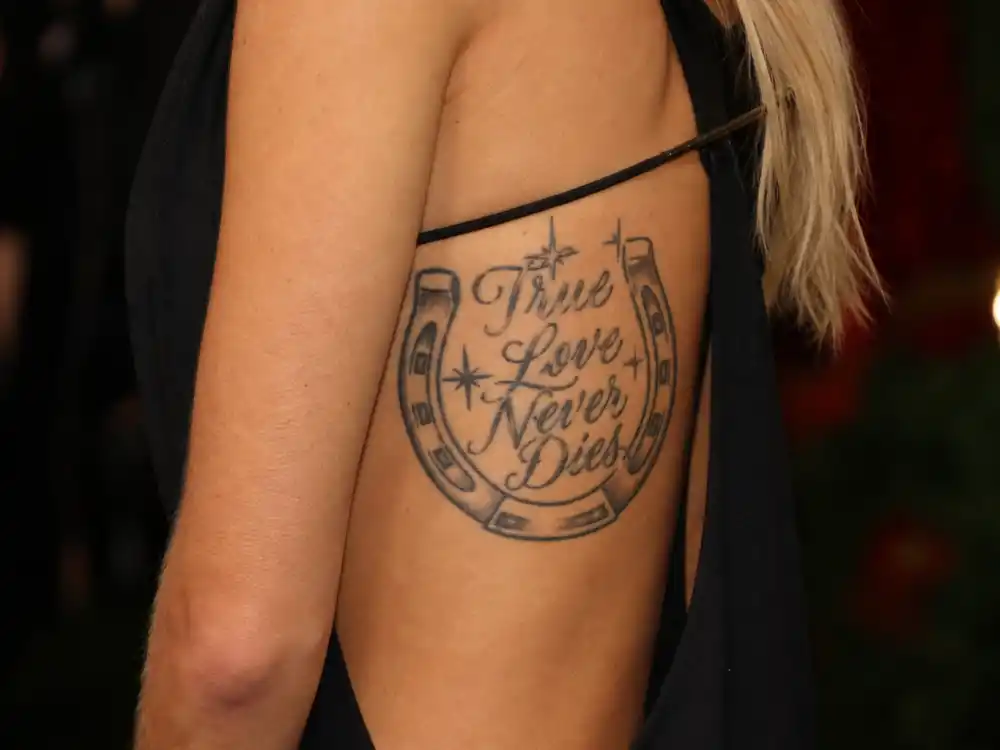 Scarlett Johansson tattoos and their meanings — Lucky You horseshoe script tattoo on right ribcage at Vanity Fair party