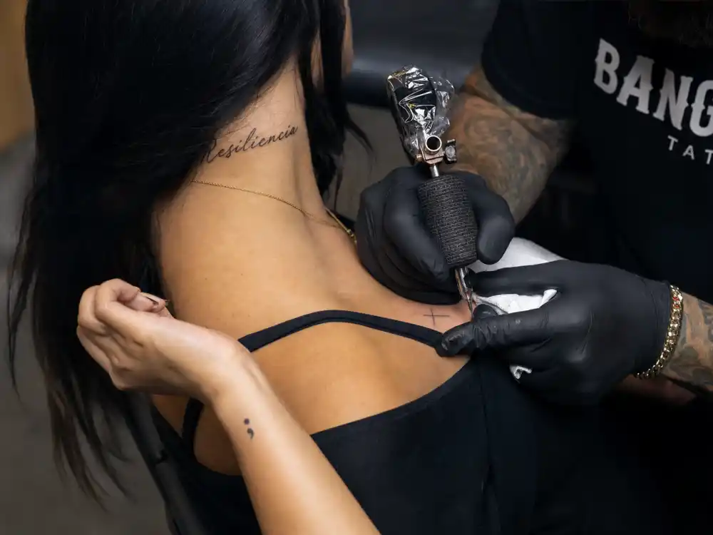 Selena Gomez tattoos and their meanings — Bang Bang tattoo artist applying collarbone cross during NYC studio session