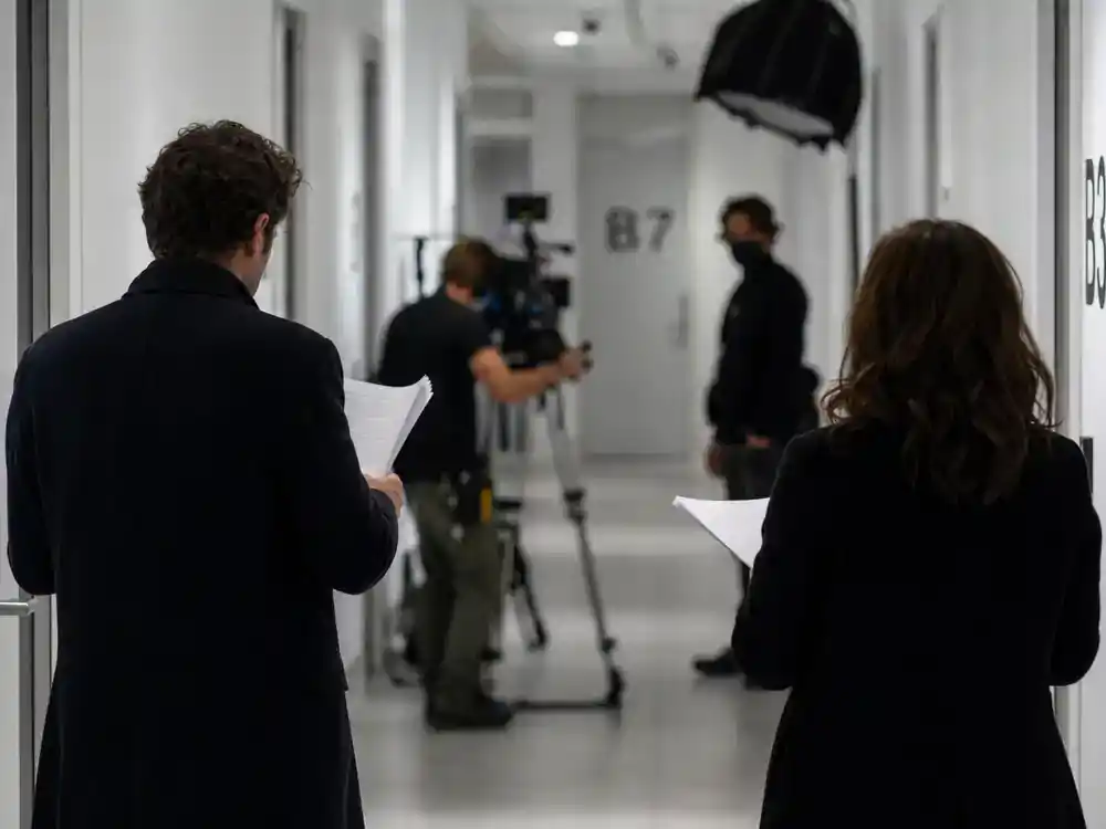 Severance season 2 cast and plot guide Britt Lower Helly R — actor silhouettes from behind rehearsing in sterile white corporate hallway film set