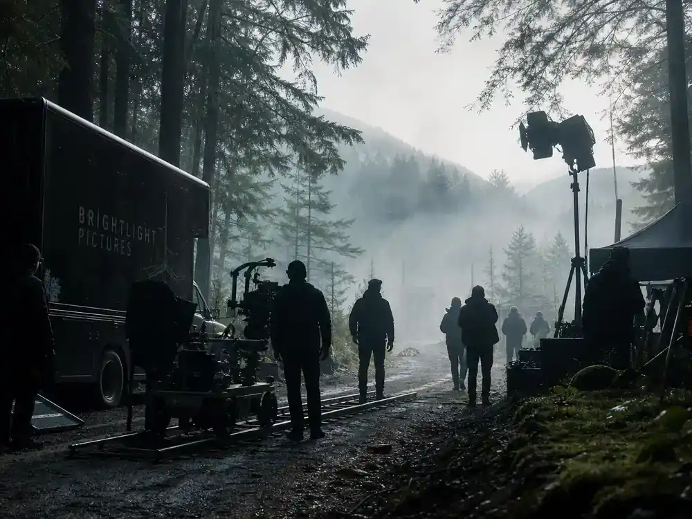 Shogun FX cast and characters guide Vancouver filming — TV drama production trucks and crew silhouettes scouting misty Pacific Northwest forest location with camera dolly