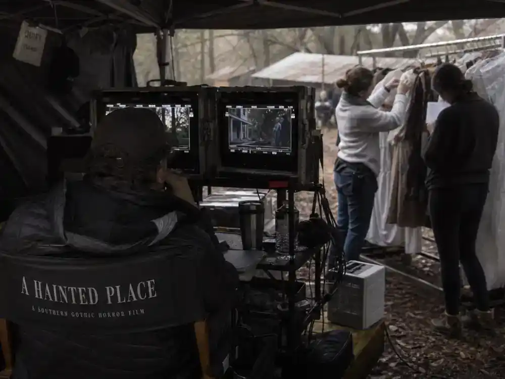 Sinners movie cast and Ryan Coogler guide director — filmmaker silhouette from behind at video village on 1930s horror film set reviewing monitors