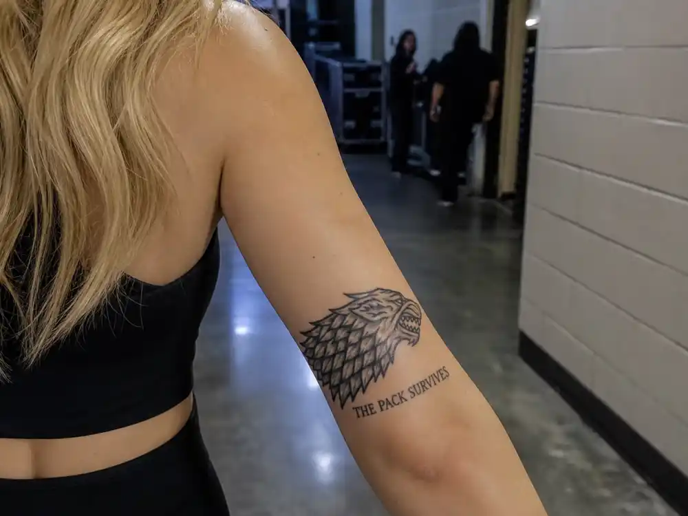 Sophie Turner tattoos and their meanings direwolf — House Stark sigil with the pack survives script on left forearm Game of Thrones tribute