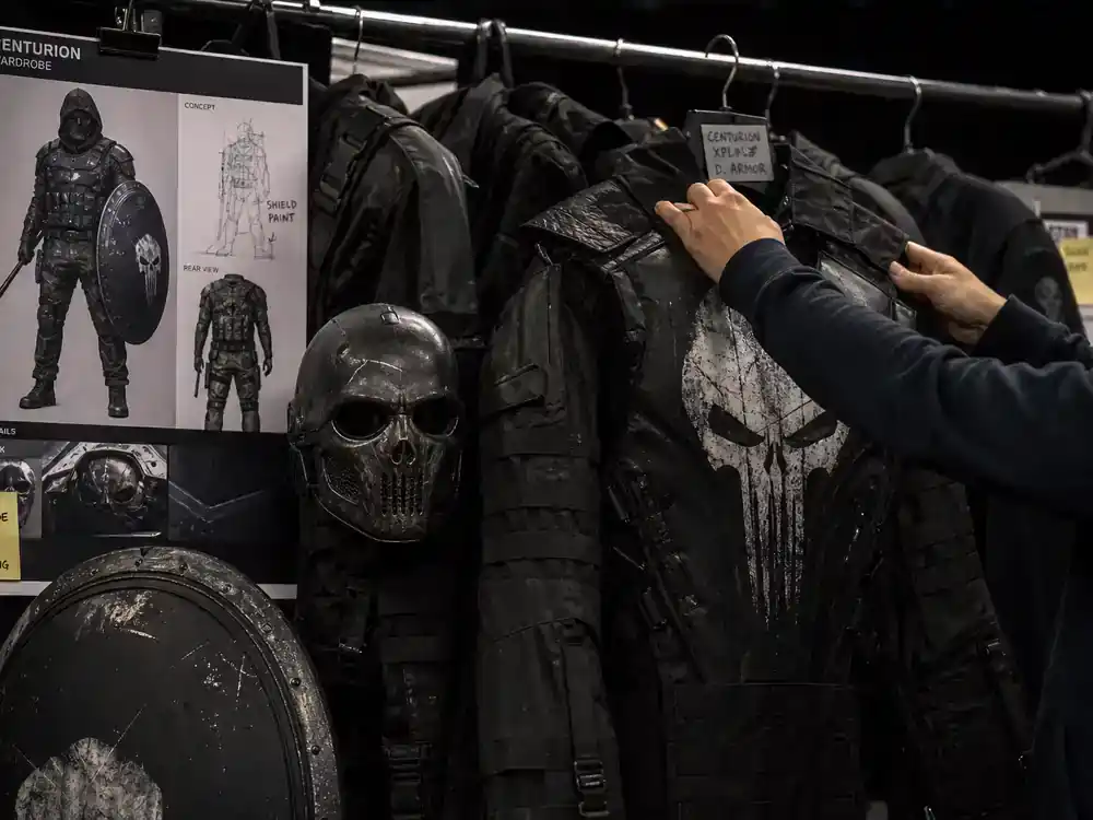 Spider-Man Brand New Day cast and characters guide villains — antagonist wardrobe rack with tactical costume pieces on film set, no faces visible