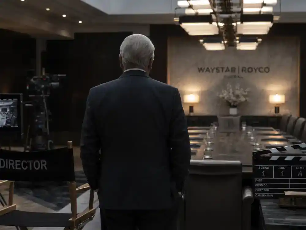 Succession cast and characters guide Logan Roy — patriarch actor silhouette from behind on corporate boardroom TV drama film set with director chair